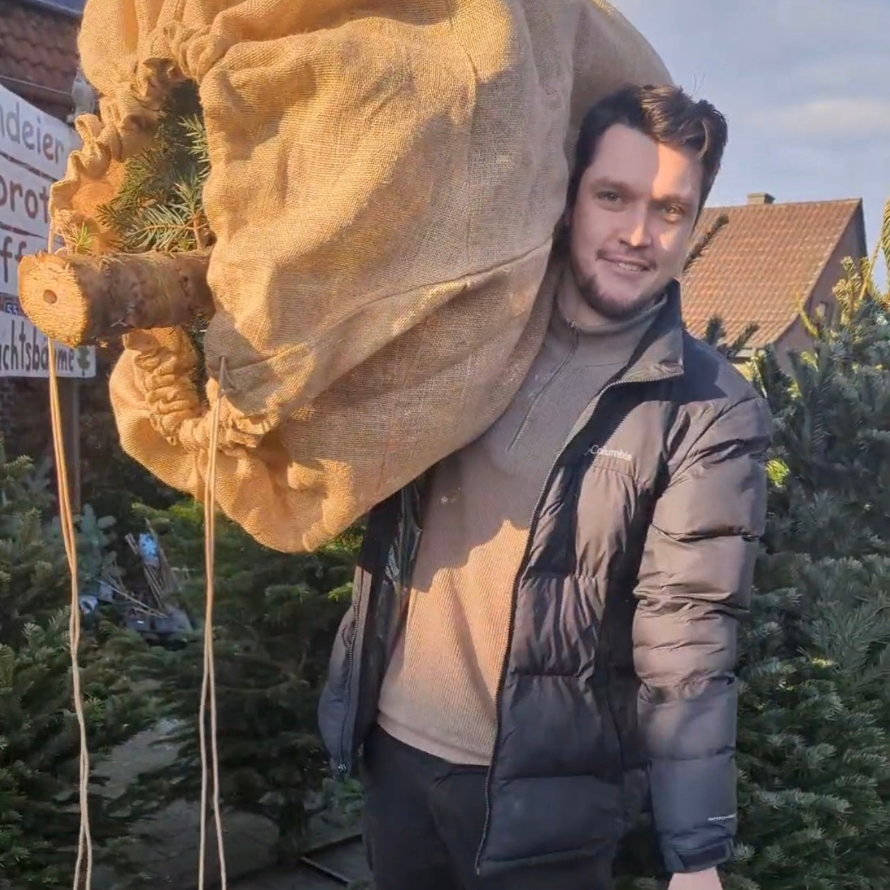 Foto - Arthur Zilleckens (Blogger) trägt einen Weihnachtsbaum verpackt in unserer nachhaltigen Weihnachtsbaum Transporthülle aus Jute